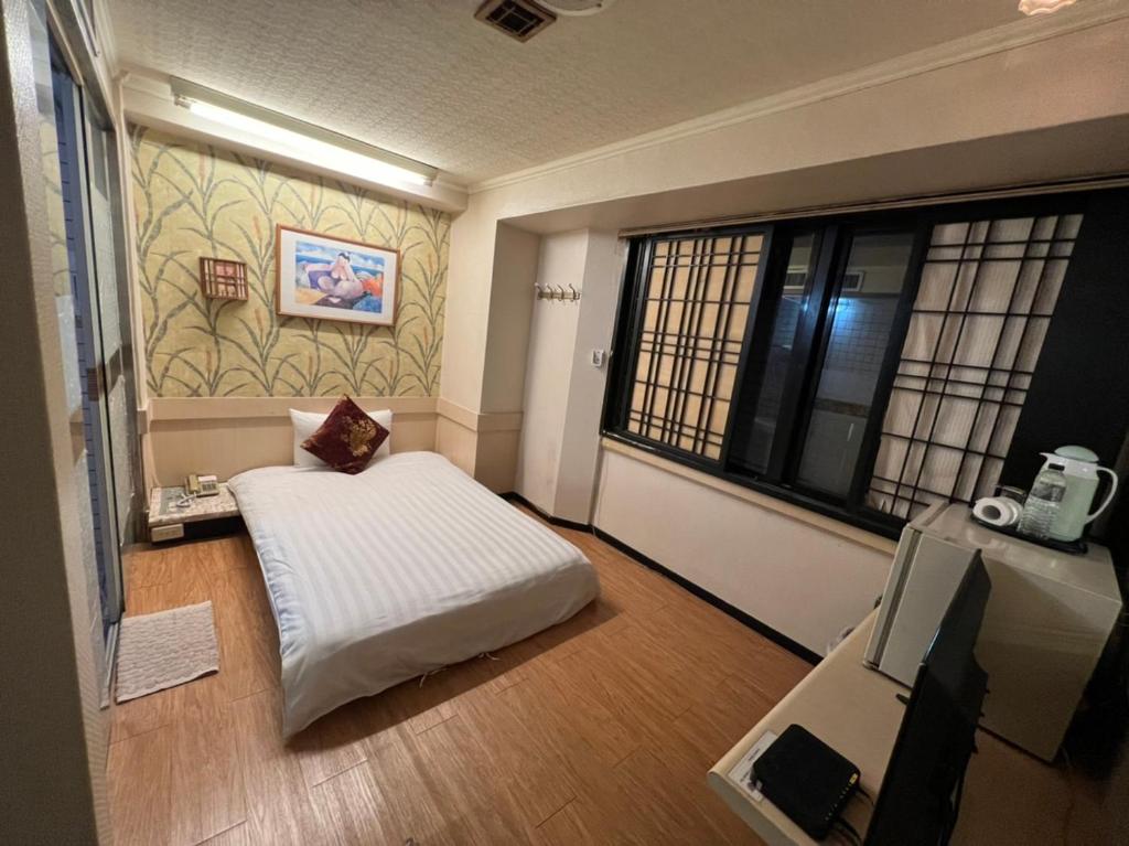 a bedroom with a white bed and a window at Boston Hotel in Chiayi City