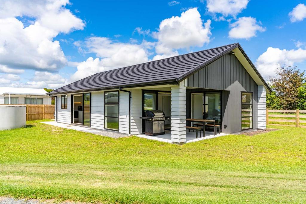 ein kleines weißes Haus auf einem Grasfeld in der Unterkunft Sweet and Stylish - Mangawhai Heads Holiday Home in Mangawhai