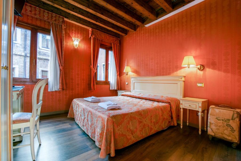 um quarto com paredes vermelhas e uma cama e uma cadeira em Lanterna Di Marco Polo em Veneza