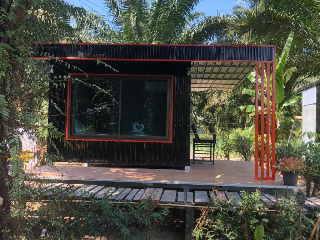 una piccola casa con una struttura rossa su una terrazza di legno di Khao Sok Blue Mountain a Parco Nazionale di Khao Sok