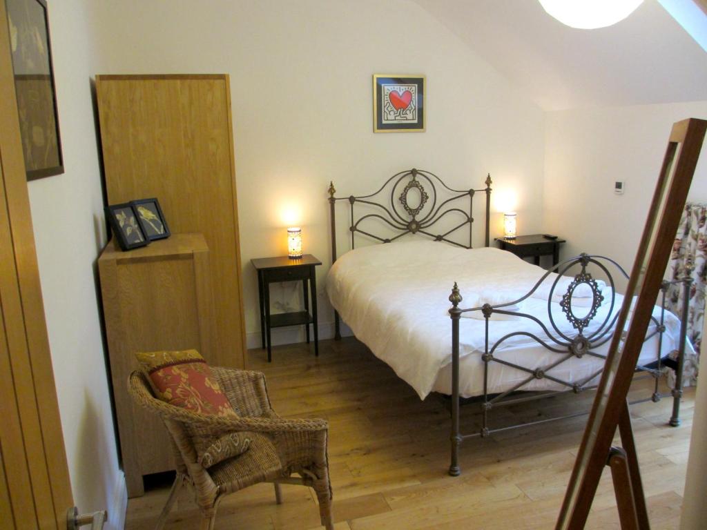 a bedroom with a bed and two tables and a chair at Acorn Chapel - Beautiful Converted Chapel in Norwich