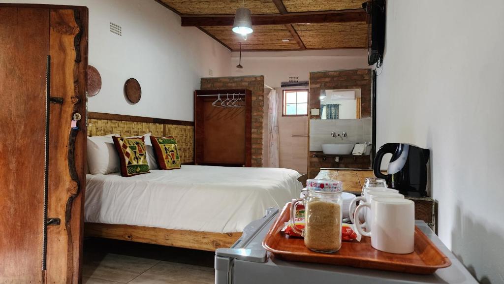 a bedroom with a bed and a bathroom with a sink at Nxabii Cottages in Kasane