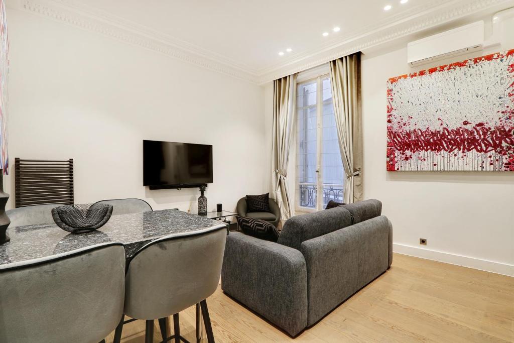 ein Wohnzimmer mit einem Sofa und einem Tisch in der Unterkunft Pick A Flat's Apartment in Triangle d'Or - Pierre 1er de Serbie in Paris