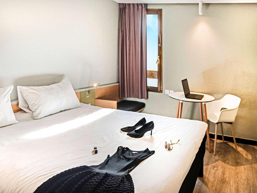 una habitación de hotel con una cama con zapatos. en ibis Strasbourg Sud La Vigie en Ostwald