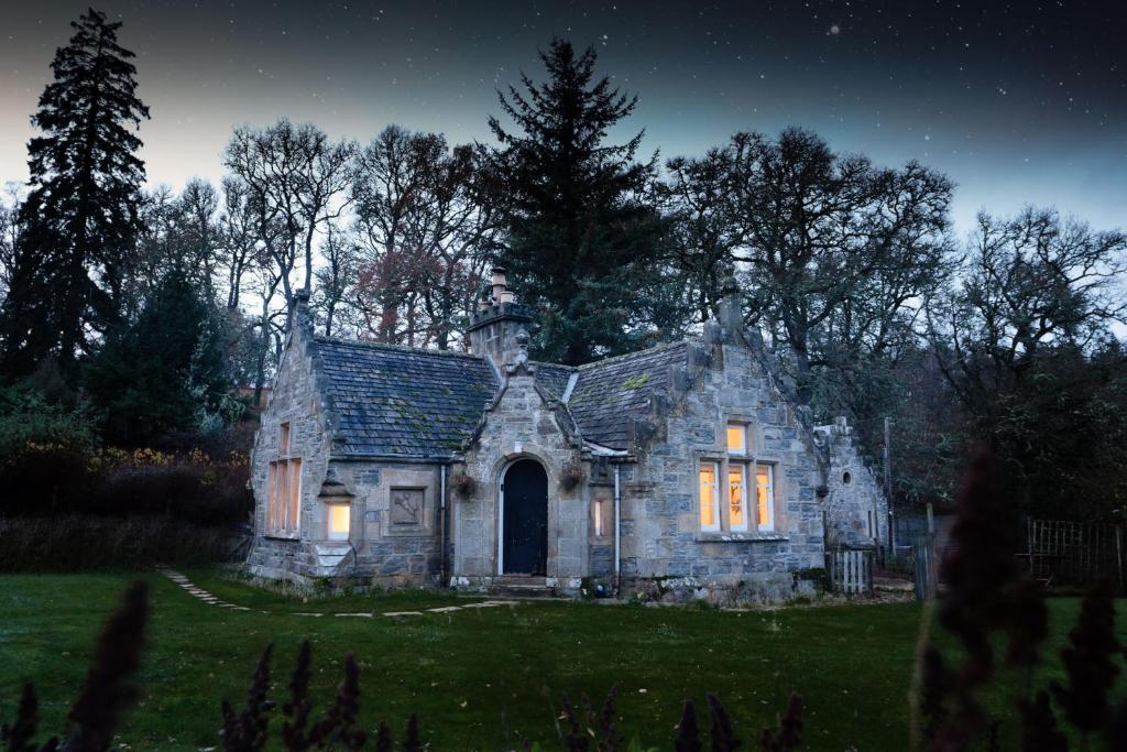 an old stone house in a field at night at West Lodge - Seasgair Lodges in Kincraig