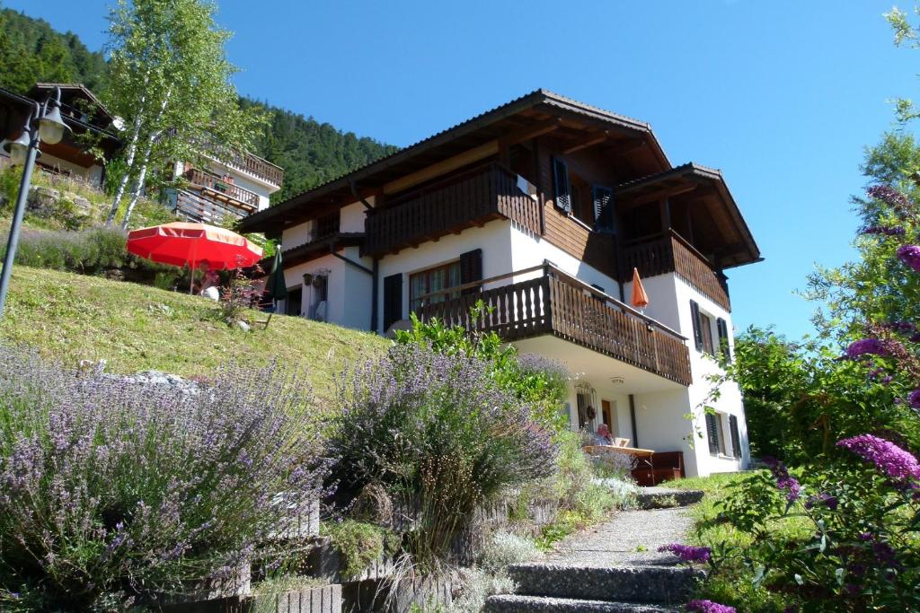 a house on the side of a hill with flowers at Ferienhaus Bensel in Alvaneu