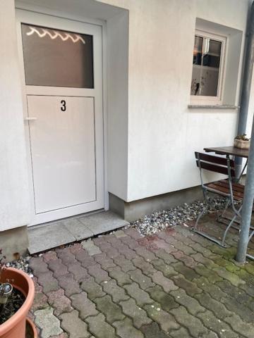 a white door with the number three next to a building at Pension da Luigi in Greifswald