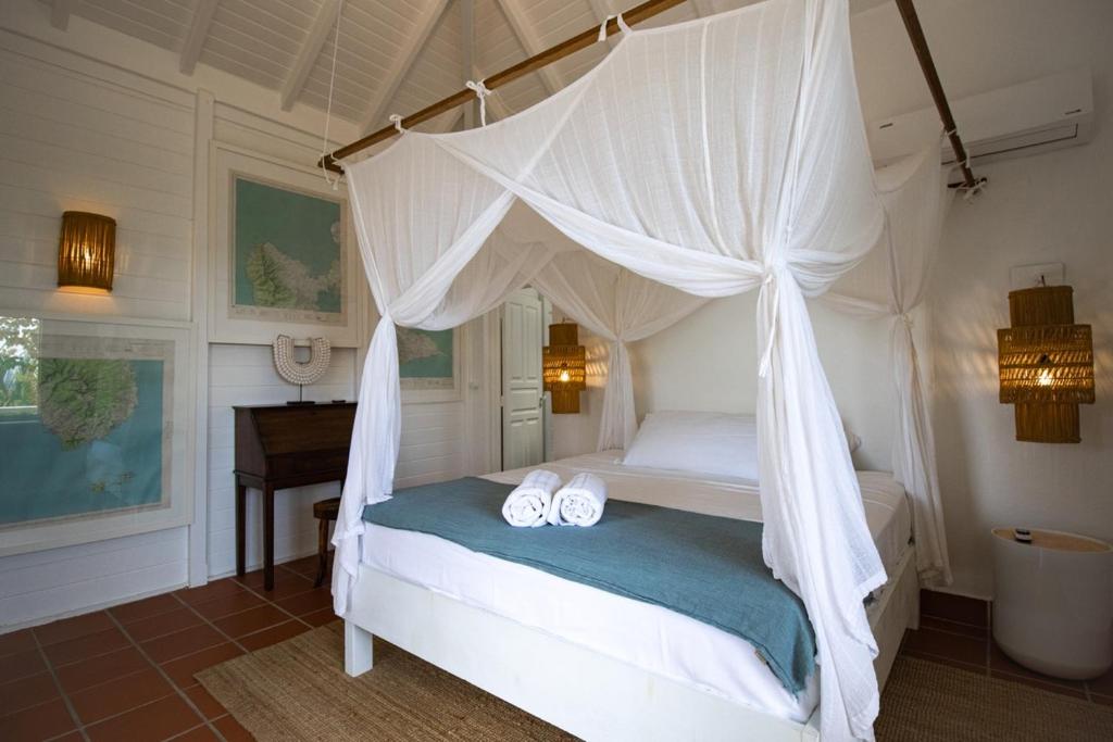 a bedroom with a canopy bed with towels on it at Villa La Vanille à Marie Galante - vue mer & piscine in Grand-Bourg