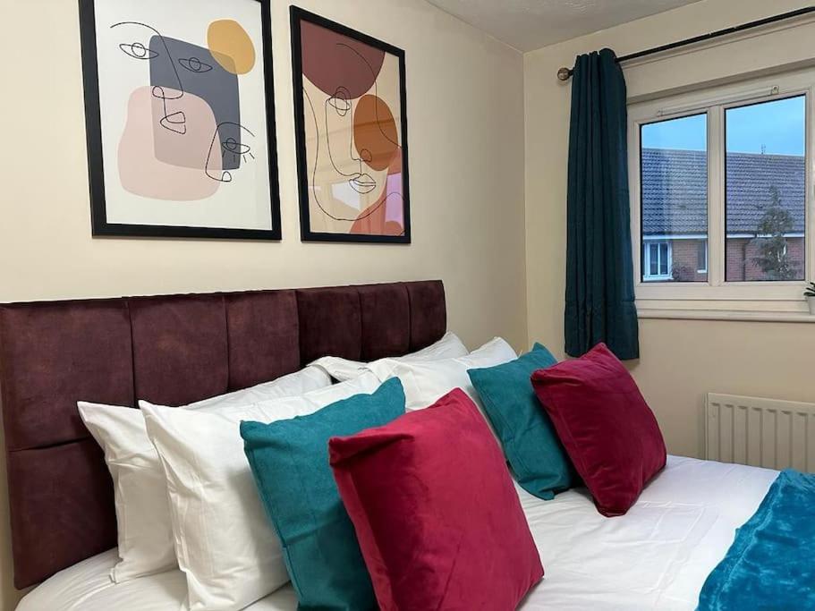 斯溫頓的住宿－Bilborough House - Comfy furnitures, Free Wifi and Free Parking，一间卧室配有带色彩缤纷枕头的床。
