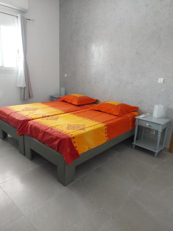 a bed with orange and yellow sheets in a room at Keur M et M in Saly Portudal