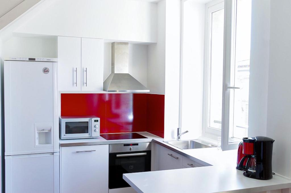 a kitchen with white cabinets and a microwave oven at Sainte Catherine - Duplex 1 chambre in Bordeaux