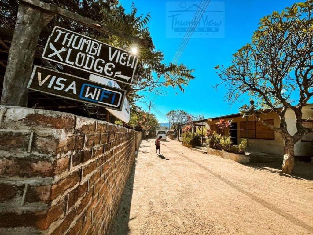 a person walking down a dirt road next to a brick wall at Thumbi View Lodge in Cape Maclear