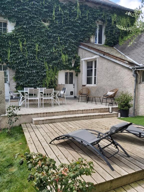 ein Haus mit einer Holzterrasse mit einem Tisch und Stühlen in der Unterkunft Gite de charme au bord de l'Indre avec jacuzzi in Monts