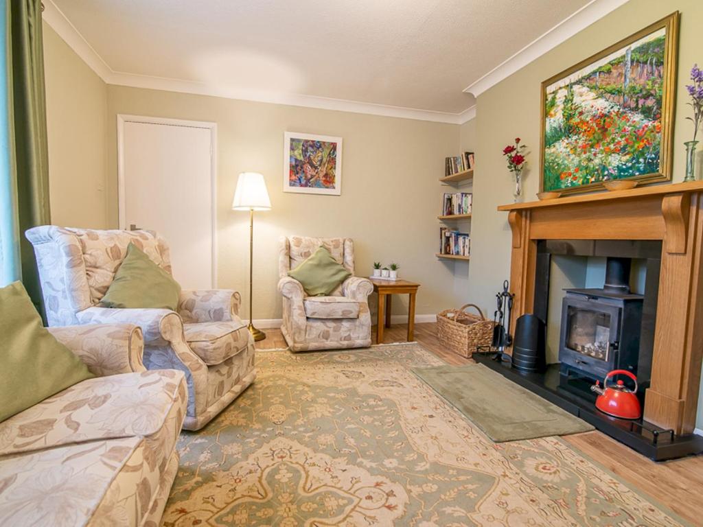 a living room with a fireplace and two chairs at Pass the Keys The Brook a fresh house with a unique outlook in Worcester