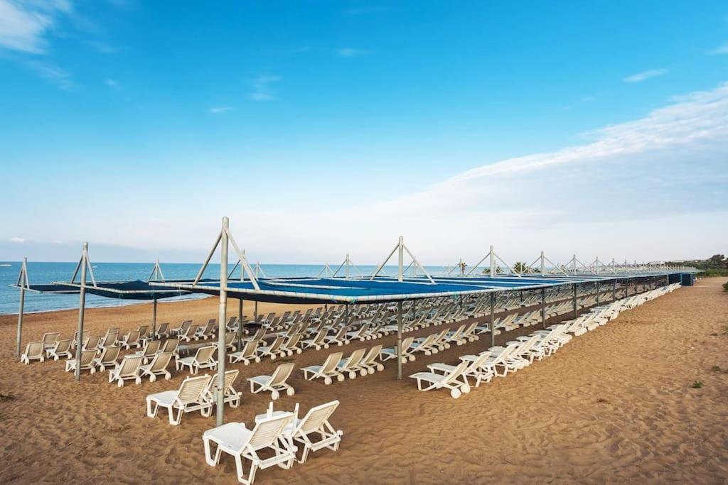 una larga fila de sillas en la playa en 3+1 COZY SUMMER APARTMENT WITH PRIVATE BEACH, en Side