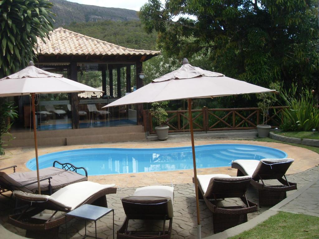 a group of chairs and umbrellas next to a pool at Pousada Papyrus in Tiradentes