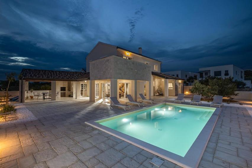 a large swimming pool in front of a house at Villa Stina Jezera, Murter in Jezera