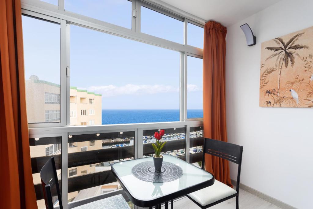 une table et des chaises dans une chambre avec une grande fenêtre dans l'établissement Home2Book Candemar Ocean View, à Candelaria