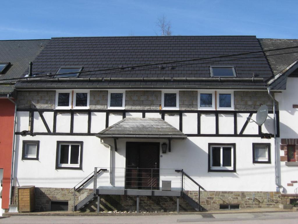 ein großes weißes Gebäude mit schwarzem Dach in der Unterkunft Das Kleine Glück in Büllingen