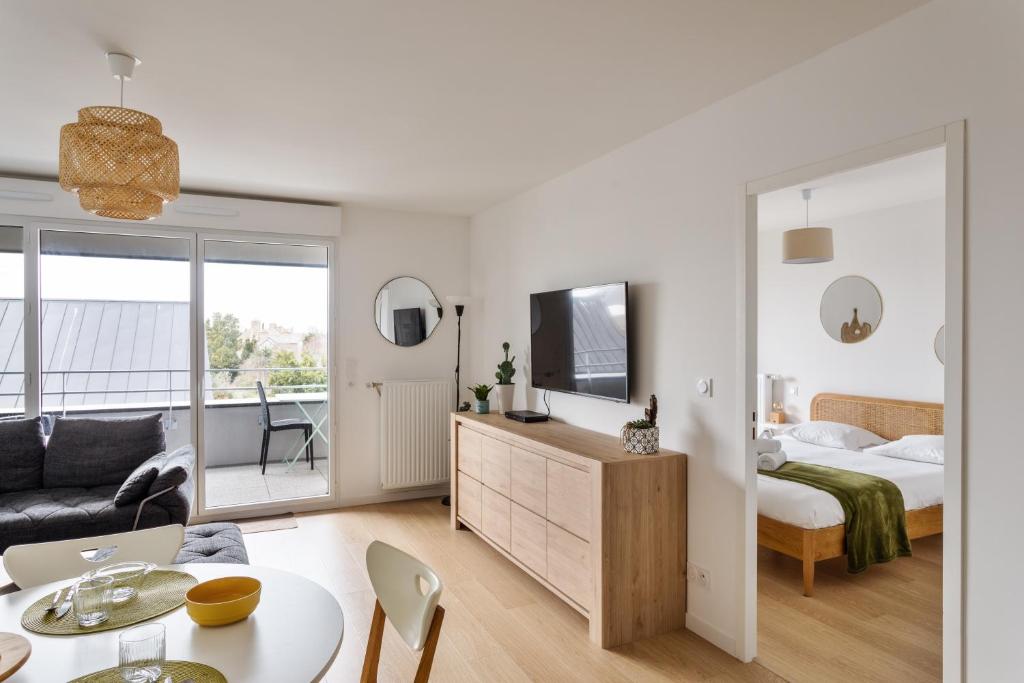 sypialnia i salon z łóżkiem i telewizorem w obiekcie Le Rochenoire - Appt proche plage w mieście Dinard