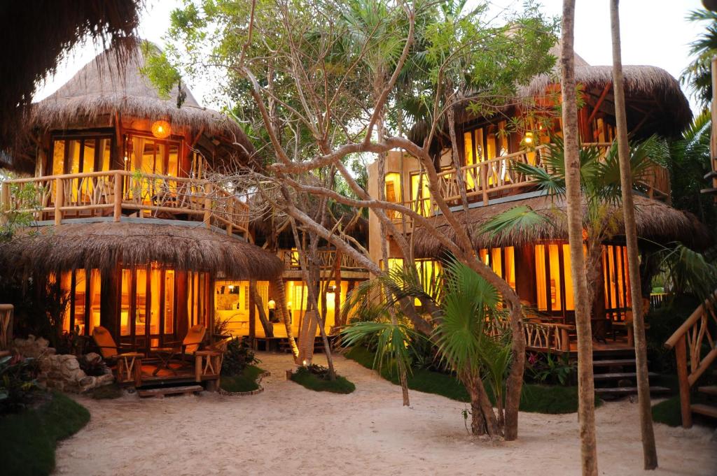 a large house with thatched roofs and trees at Alaya Beachfront Tulum Hotel in Tulum