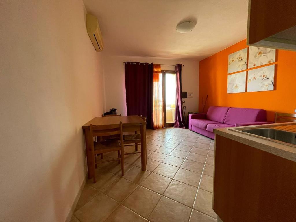 un soggiorno con divano viola e tavolo di Residence La Spiga a Castelsardo