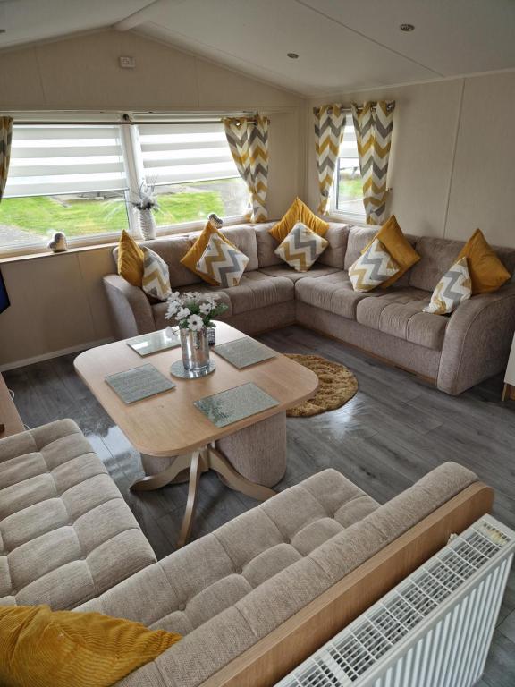 a living room with a couch and a table at 3 bedroom Caravan Craigtara in Ayr