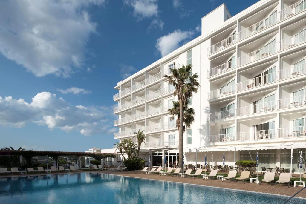 un hotel con piscina frente a un edificio en Seth Agamenon en Es Castell