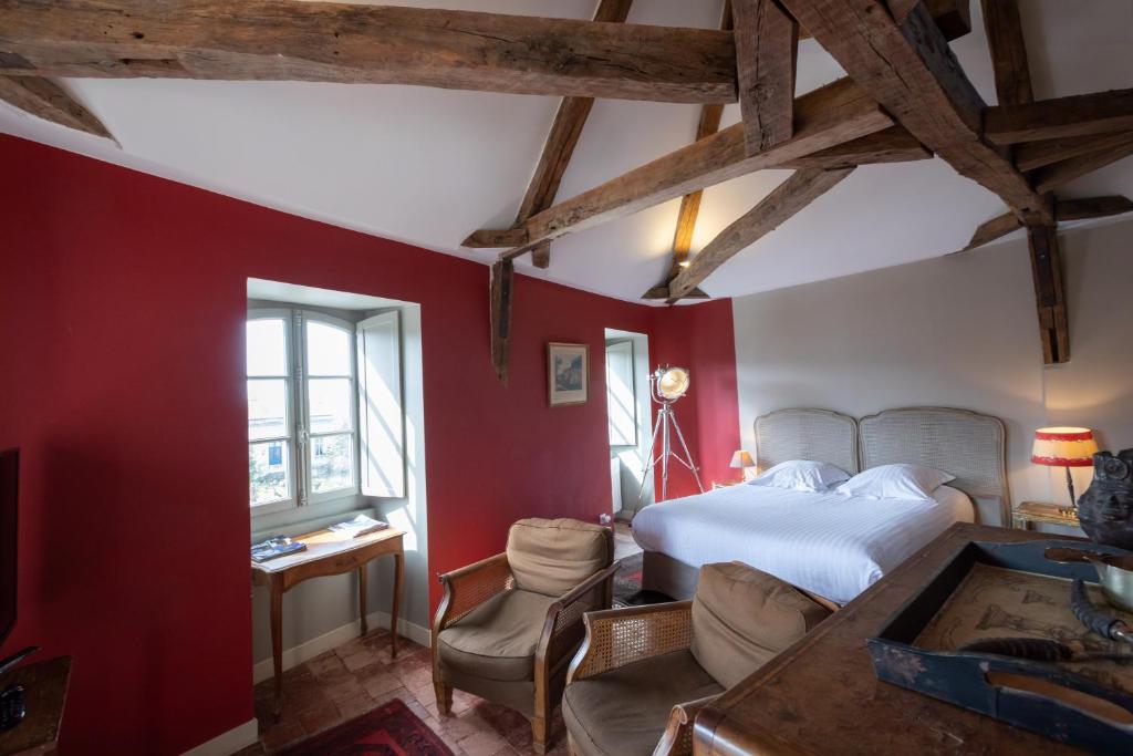 a bedroom with red walls and a bed and a desk at L'hôtel de Panette, chambres indépendantes, charpente historique in Bourges