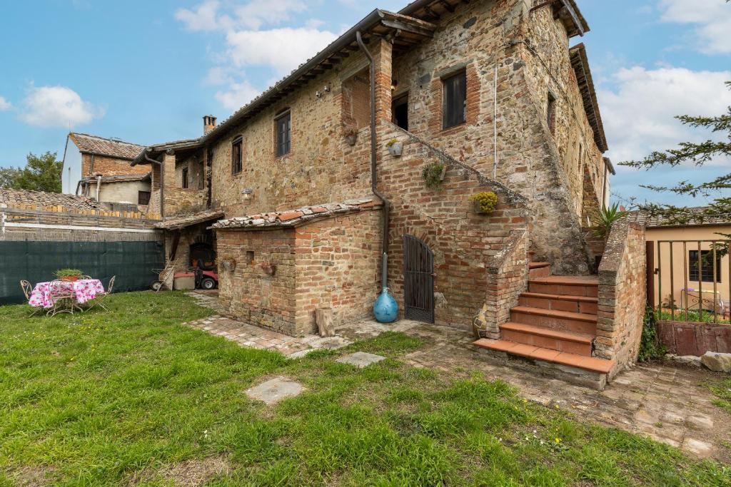 an old brick house with a staircase in a yard at La Badia in Gambassi Terme