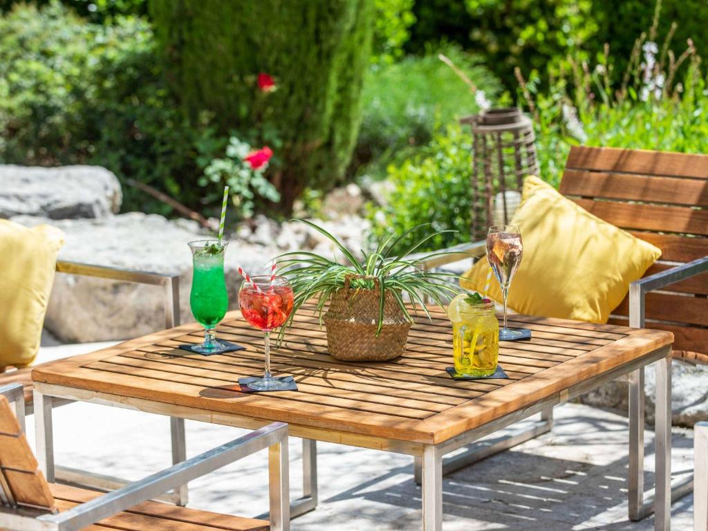 een houten tafel met twee glazen erop bij Novotel Aix-en-Provence Beaumanoir in Aix-en-Provence