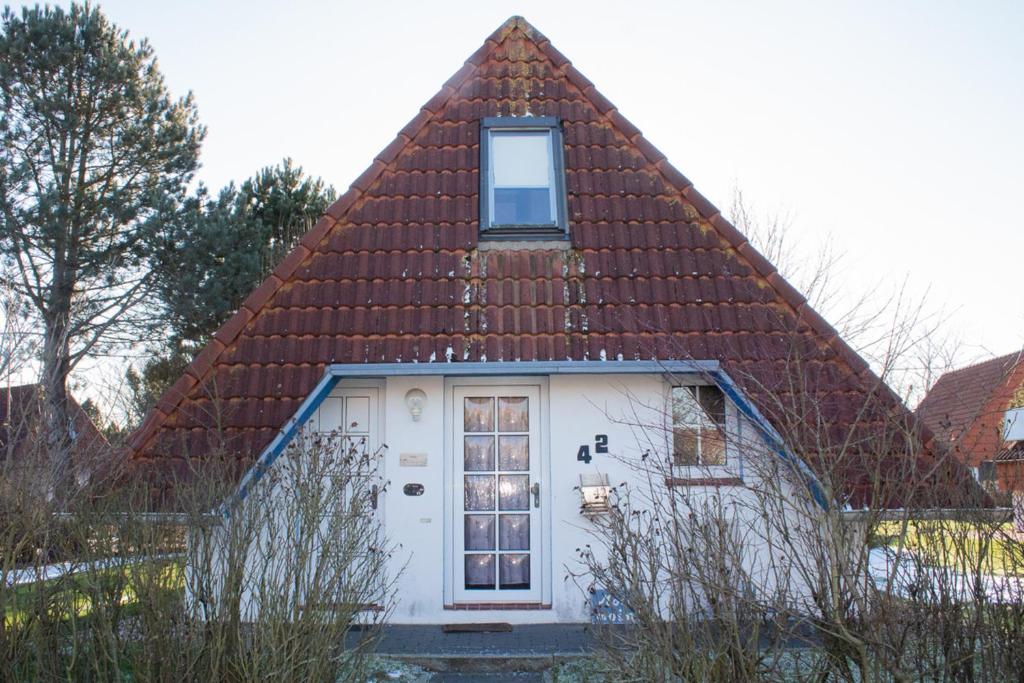 ein kleines weißes Haus mit braunem Dach in der Unterkunft OH 42 - Strandvogt Komfort in Dorum Neufeld