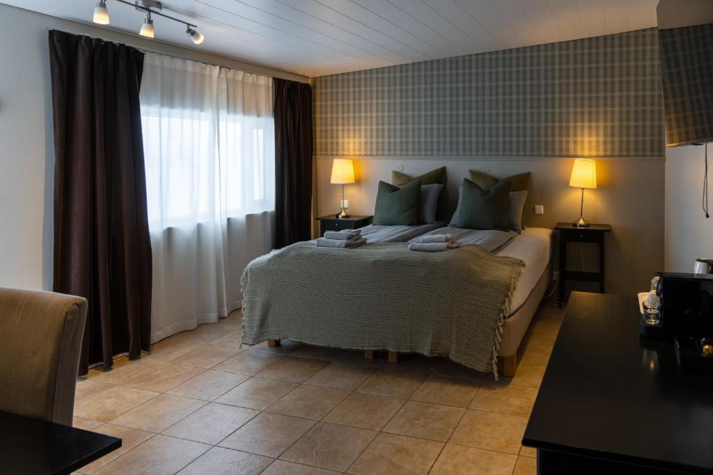 HOTEL SNAEFELLSNES formally Hotel Rjukandi في Vegamót: غرفة نوم بسرير كبير ومخدات خضراء