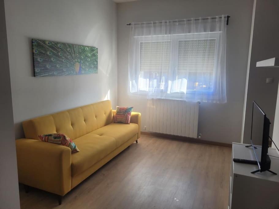 sala de estar con sofá amarillo y TV en Apartamento kuko con wifi al lado metro, en Bilbao