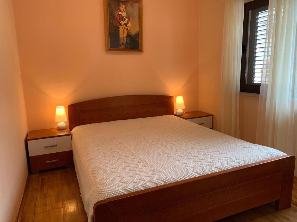 a bedroom with a bed with two lights on it at Apartments Nives in Smokvica
