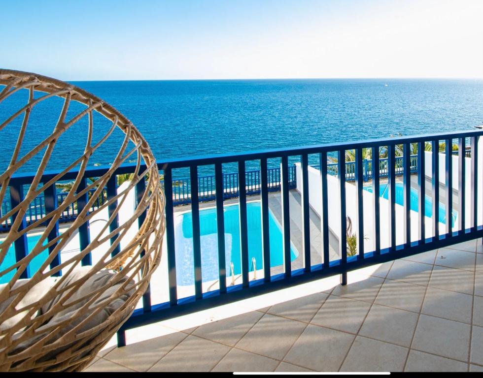 una silla de mimbre sentada en un balcón con vistas al océano en FRONTLINE VILLA 25, Modern Coastal Design with Amazing Views, en Puerto Calero