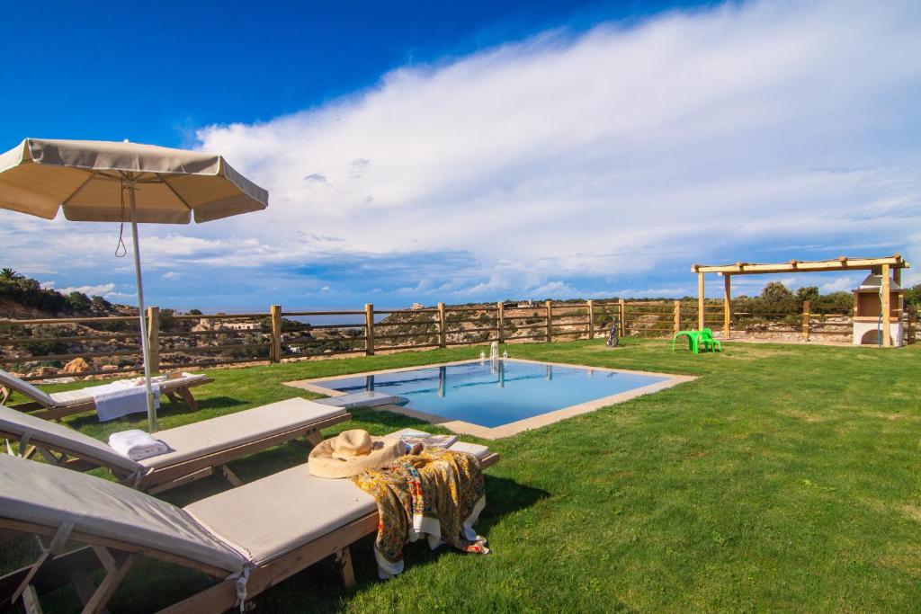einen Pool in einem Garten mit zwei Stühlen und einem Sonnenschirm in der Unterkunft Chainteris Villas, a Summer Dream, By ThinkVilla in Prínos