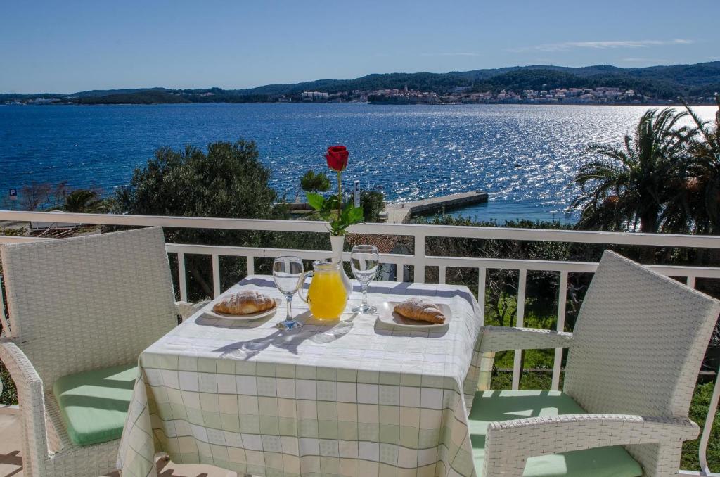 una mesa con comida y bebida en un balcón con vistas al agua en Bed & Breakfast Villa Vrgorac, en Orebić