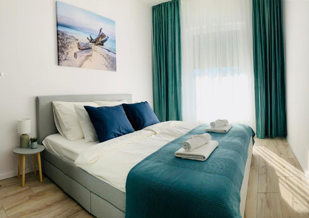 ein Schlafzimmer mit einem Bett mit einem blauen Ottomanen in der Unterkunft Przystań Letników by MYPART in your apartment in Danzig