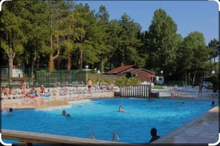 une grande piscine avec de nombreuses personnes dans l'établissement Camping la dune blanche, à Camiers