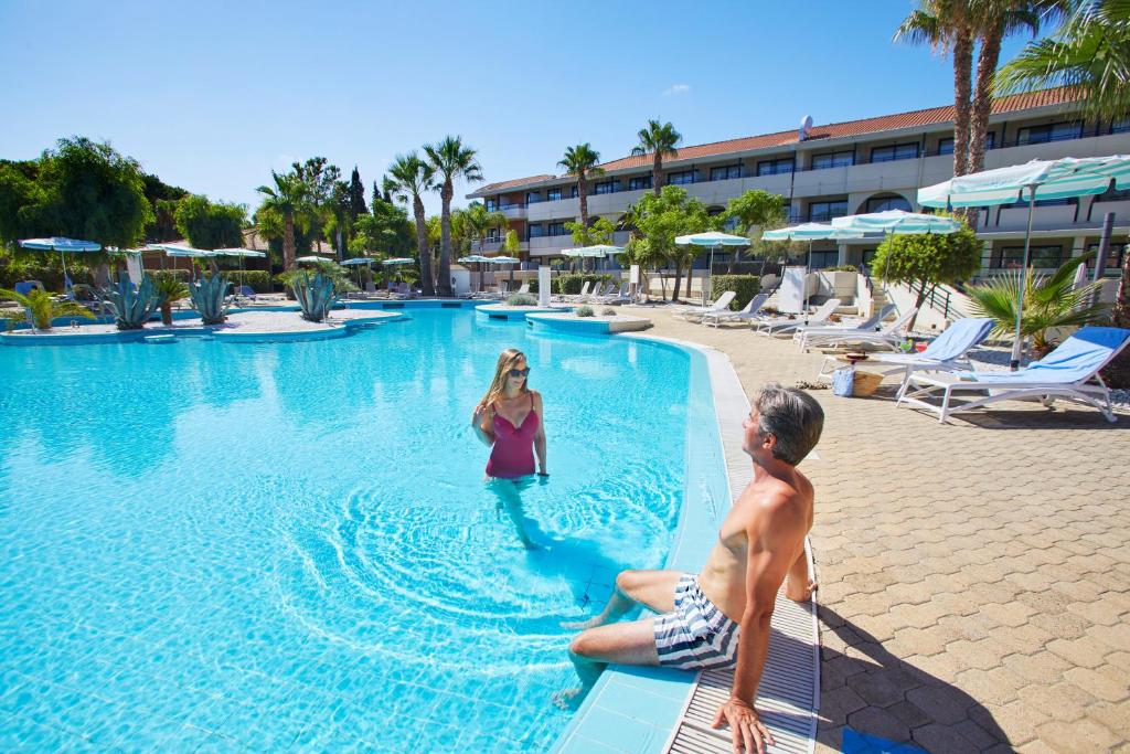 een man en vrouw in een zwembad in een resort bij The Signature Level at Grand Palladium Sicilia Resort & Spa in Campofelice di Roccella