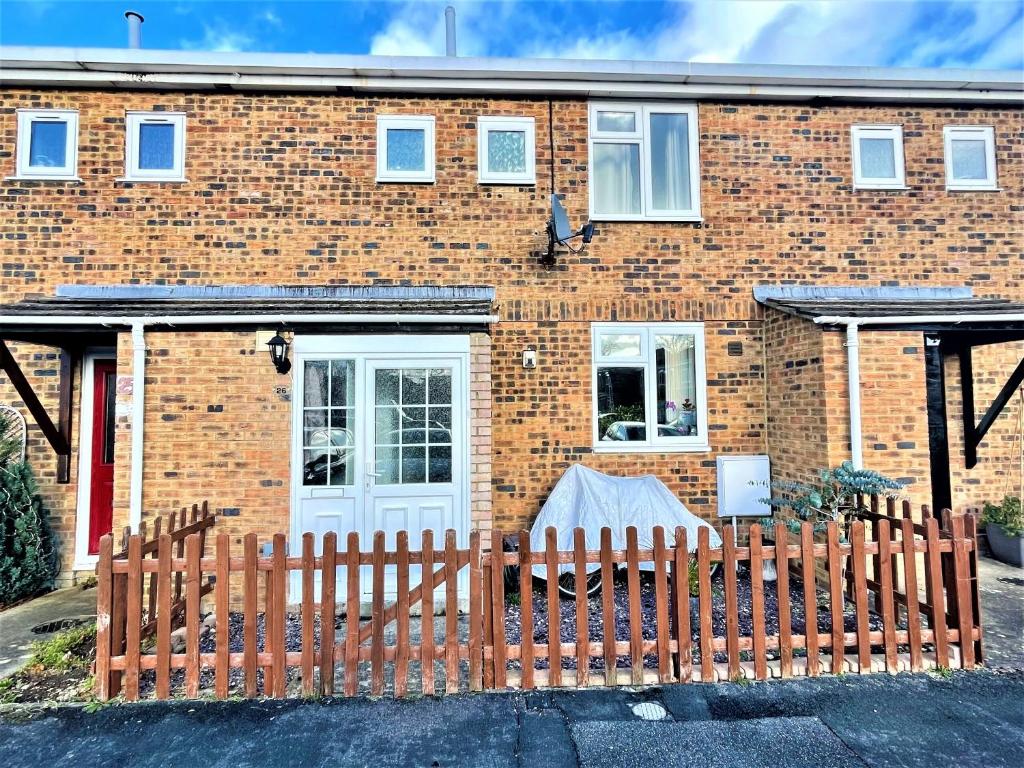 a brick house with a wooden fence in front of it at The HK House - Family Friendly Near To Blenheim Palace & Oxford City Centre in Kidlington