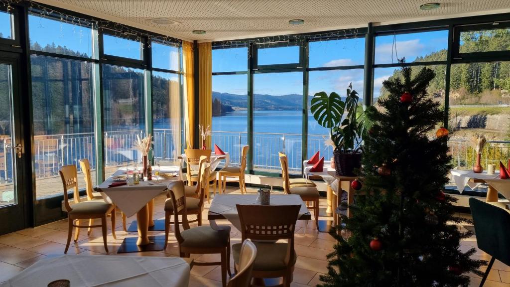 un restaurante con un árbol de Navidad en una habitación con ventanas en Seehotel Hubertus, en Schluchsee