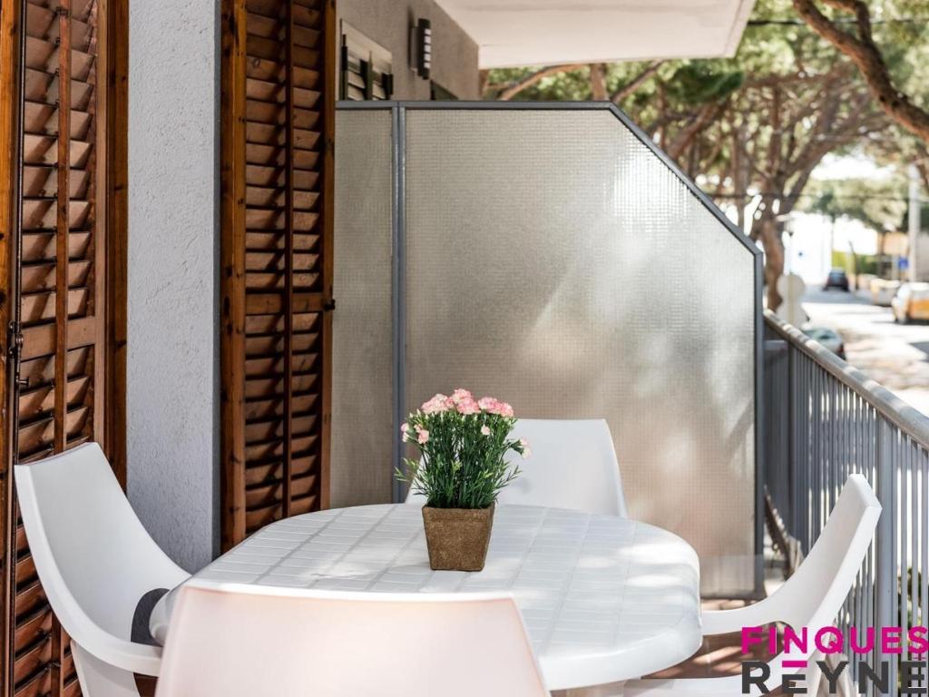 einen weißen Tisch und Stühle auf einem Balkon mit einer Blumenvase in der Unterkunft Sant pere 11 in Platja  d'Aro