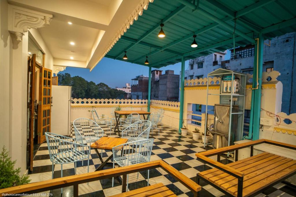Ostel By Orion Hotels -Udaipur في أودايبور: شرفة على طاولة وكراسي على السطح