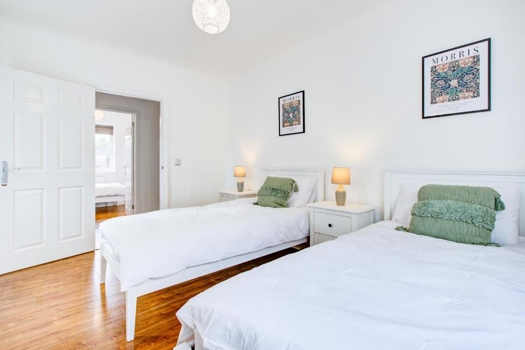 Habitación con 2 camas, paredes blancas y suelo de madera. en Stylish Two Bedroom Apartment With Free Parking! en Romford