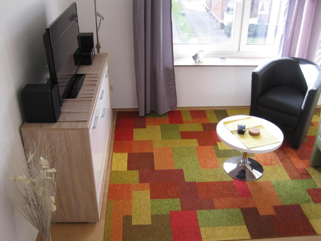 ein Wohnzimmer mit einem TV, einem Stuhl und einem Tisch in der Unterkunft Bahnhofstr Apartment in Castrop-Rauxel