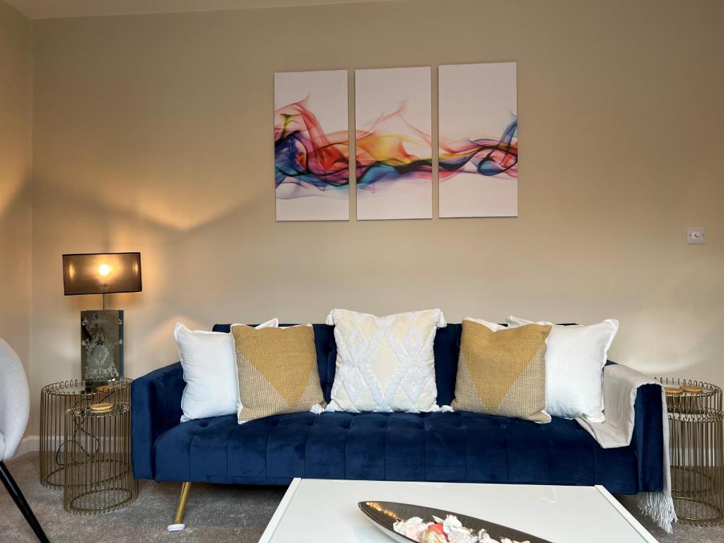 a blue couch in a living room with three paintings on the wall at Charming 4-Bed House in Winchester Free Parking in Winchester