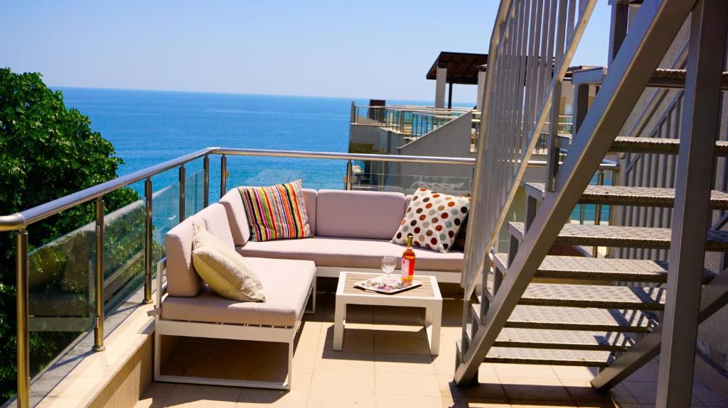 een balkon met een bank en een tafel en de oceaan bij Byala Cliff Sea View Penthouse in Byala