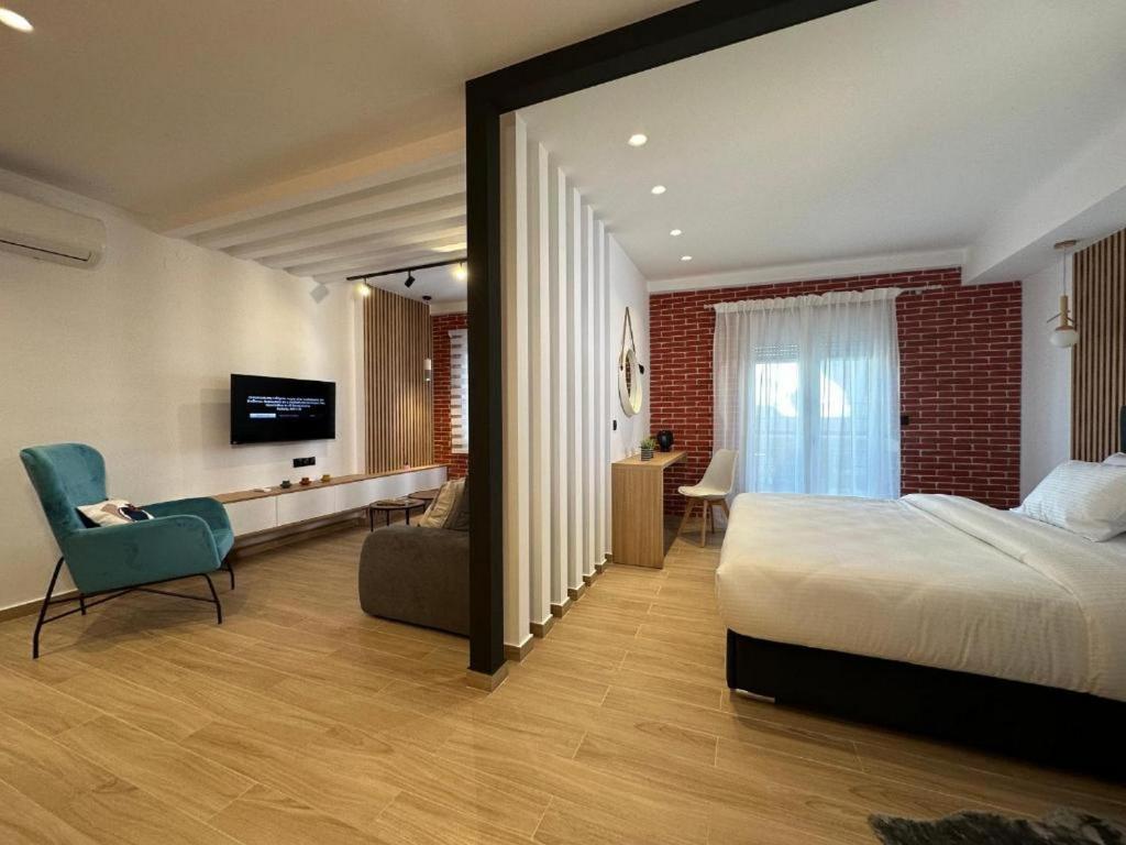 a bedroom with a bed and a chair and a television at Centro Urban Suites in Kalabaka